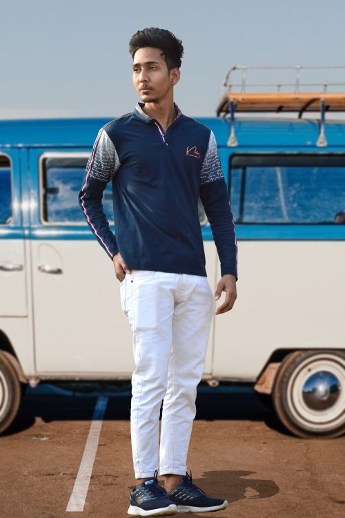 Free Confident young man in fashionable blue and white outfit standing outdoors in front of a vintage van. Stock Photo