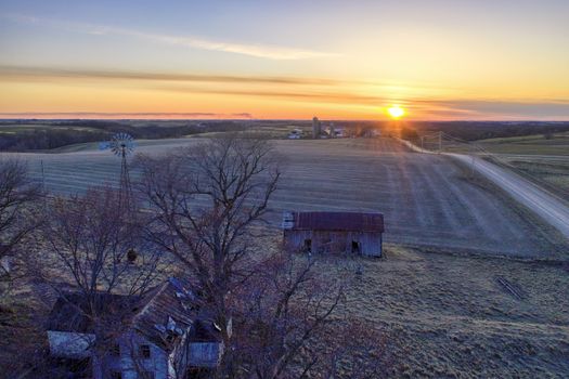 Aerial view of a peaceful Minnesota farm at sunset with rolling fields and a rustic barn.