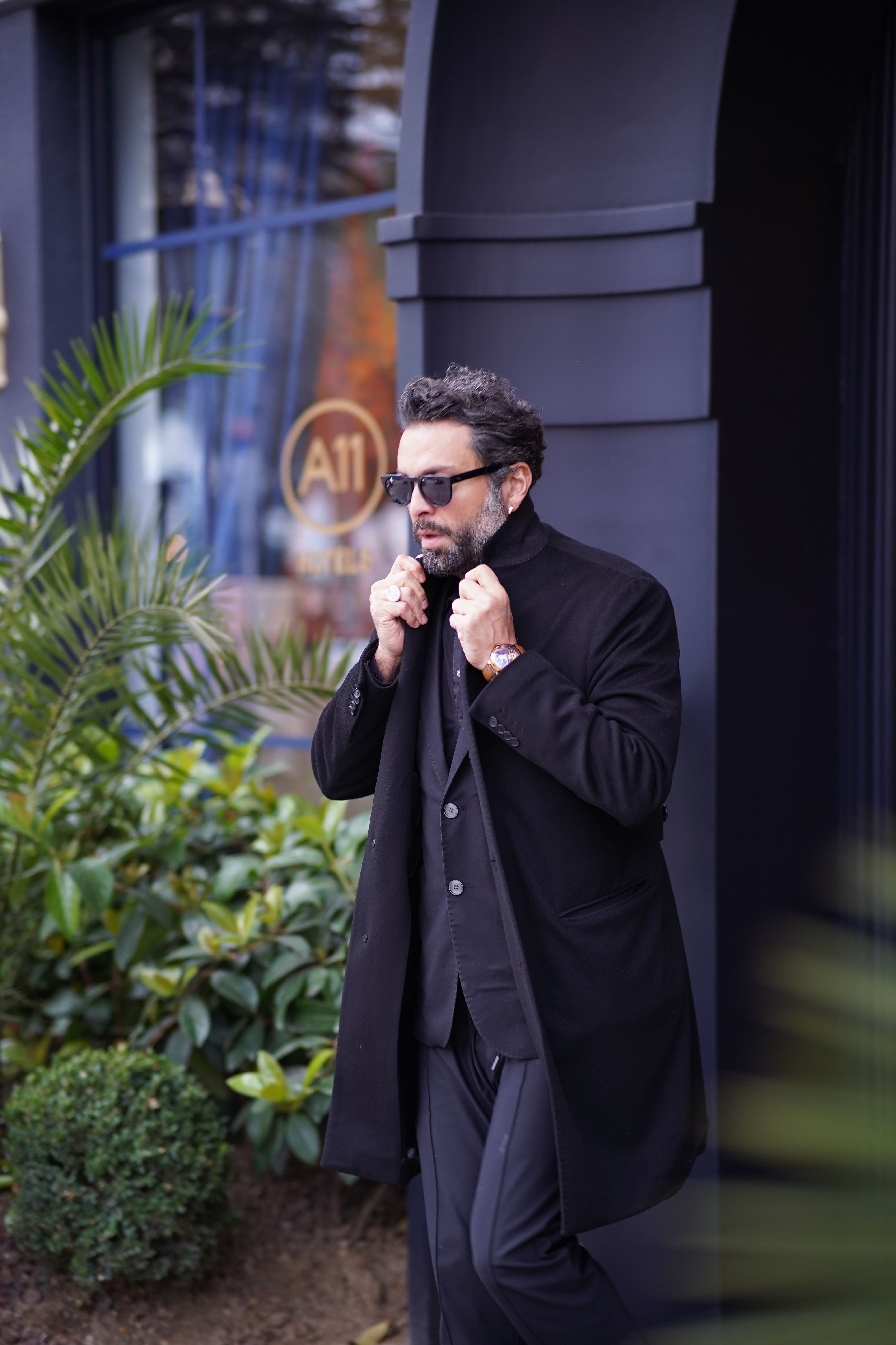 Bearded man in black trench coat with sunglasses