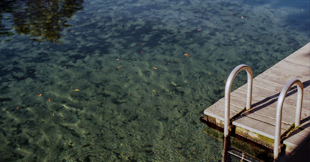 A tranquil scene at Wekiwa Springs featuring a wooden dock and crystal-clear waters, perfect for summer relaxation.