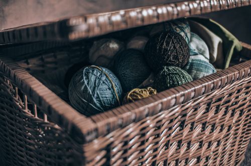 Free A close-up view of colorful yarn rolls inside an open woven basket. Stock Photo