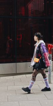 Fashion-forward young woman walking in Warsaw, showcasing vibrant street style with a colorful outfit.
