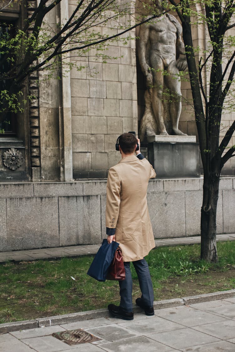 Man In Brown Coat Holding Bags