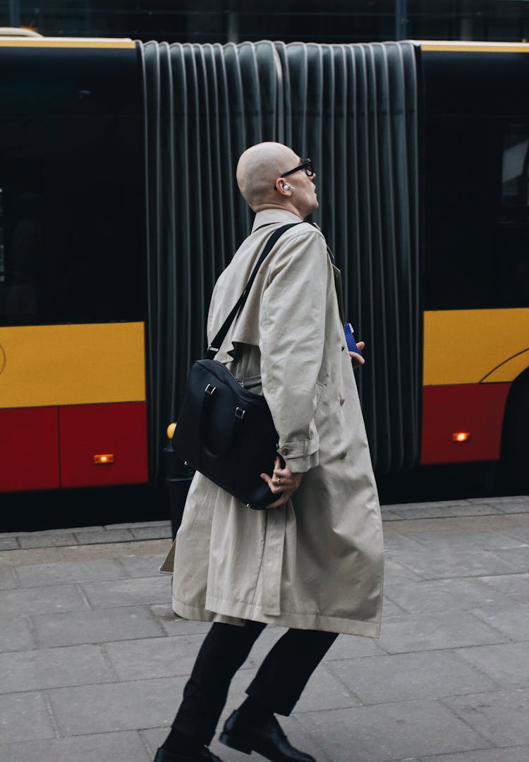 Man In Beige Coat Walking Beside A Bus