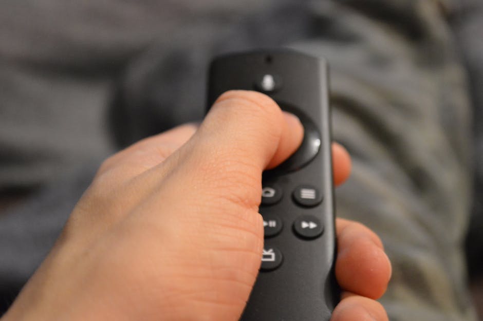 Close-up of a person's hand holding a TV remote control in Berlin, Germany.