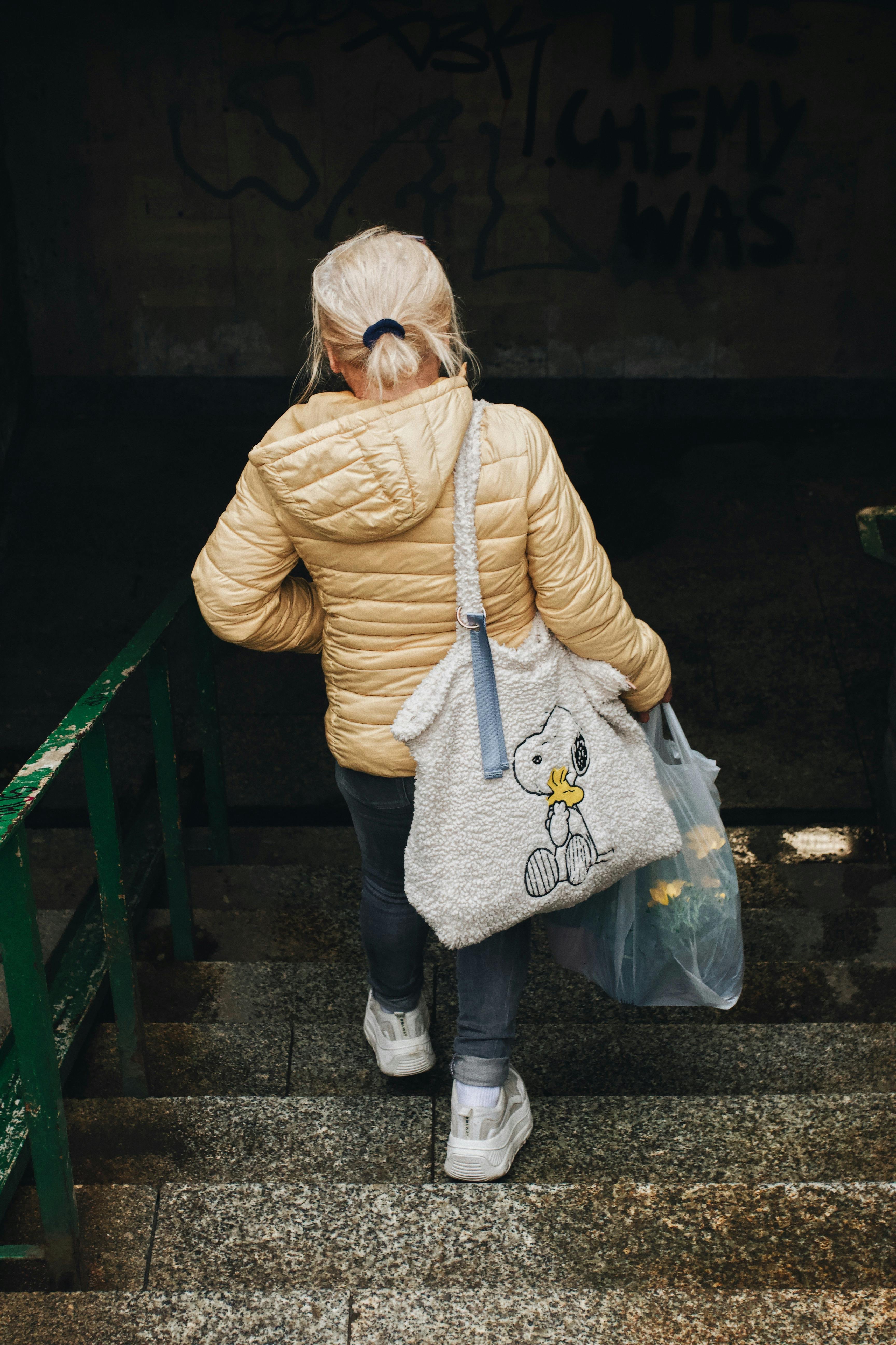 Woman with blonde hair walks down concrete stairs in Warsaw, Poland.