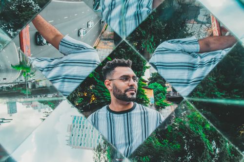 Free A creative urban portrait using mirror reflections, capturing a stylish man in Sao Paulo. Stock Photo