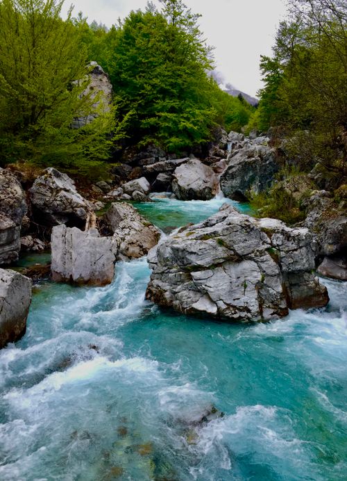 Free Breathtaking view of a turquoise river winding through a rocky forested landscape in Valbonë, Albania. Stock Photo