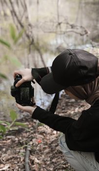 A person photographing a serene lakeside scene with a DSLR camera in an outdoor setting.
