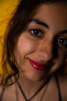 Vibrant close-up portrait of a woman with red lipstick, smiling gently against a warm backdrop.