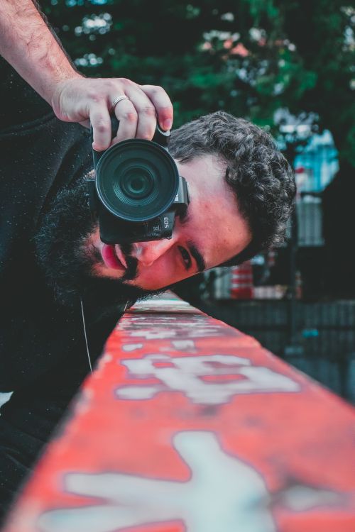 Free Close-up of a bearded photographer taking a photo with a DSLR camera outdoors. Stock Photo