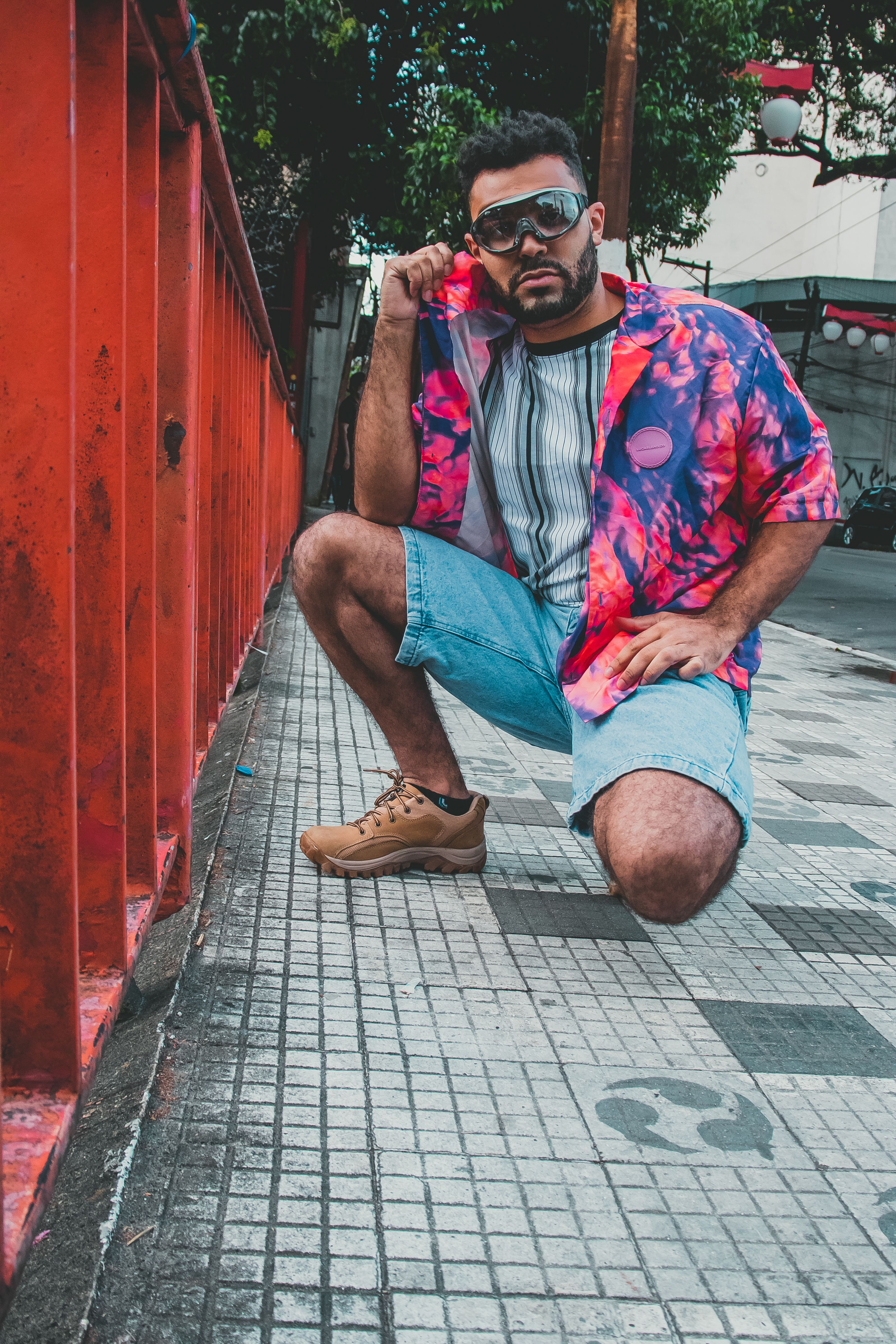Um homem estiloso posa em uma calçada da cidade, exibindo moda urbana com padrões vibrantes.