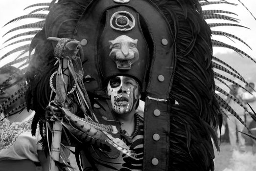 A striking black and white portrait of a man in a traditional Mexican tribal costume.
