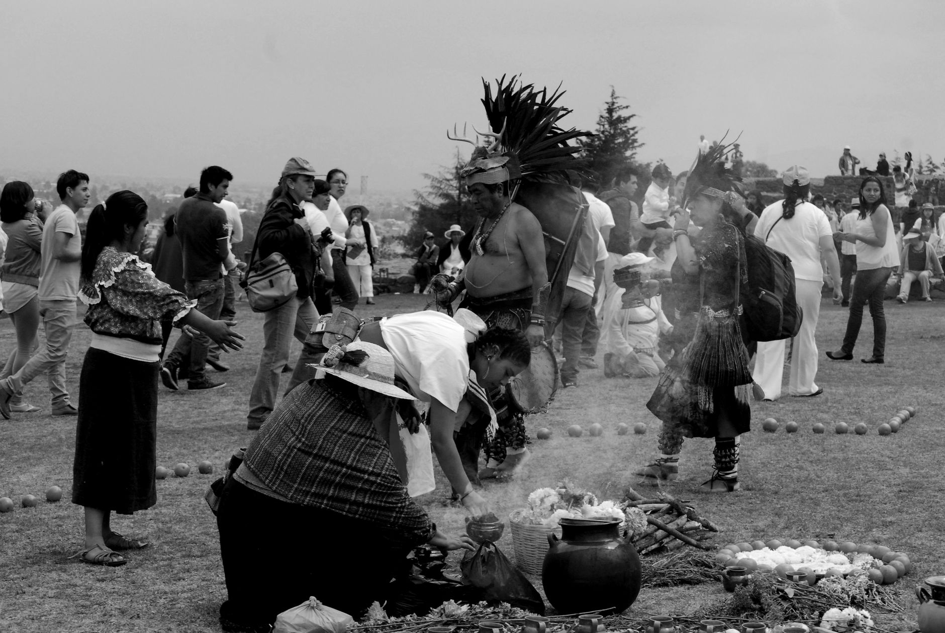 A black and white photo capturing a traditional outdoor ceremony with diverse attire.