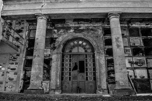 A haunting black and white image of an abandoned mausoleum with weathered columns in Junín, Argentina.