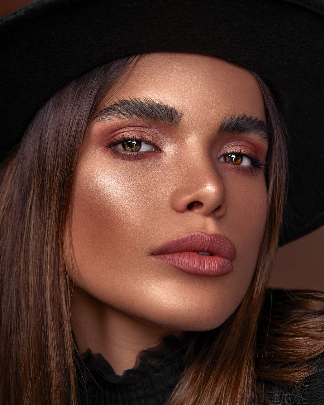 Close-up portrait of a young woman with fashionable makeup and hat.