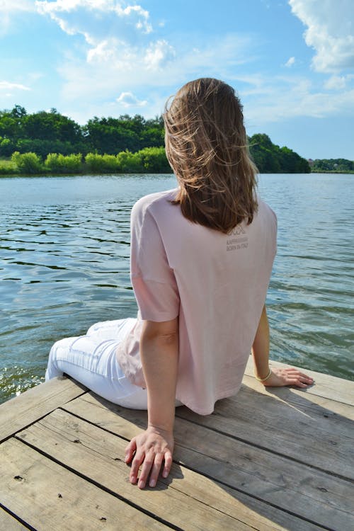 Person Sitting at the Edge of a Wooden Dock