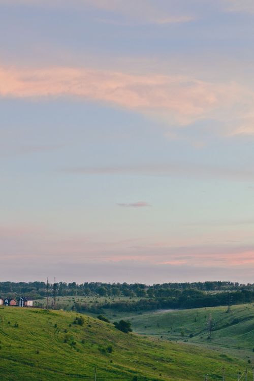 Free A peaceful rural landscape with rolling hills and a pastel sky at twilight. Stock Photo