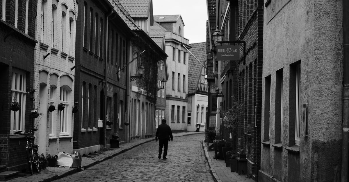 person walking alone on quiet street without phone in hand