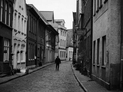Free Charming cobblestone street with a person walking, captured in monochrome. Stock Photo