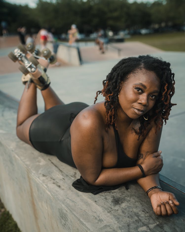 Woman In Roller Skates Lying On Stomach On Concrete Wall