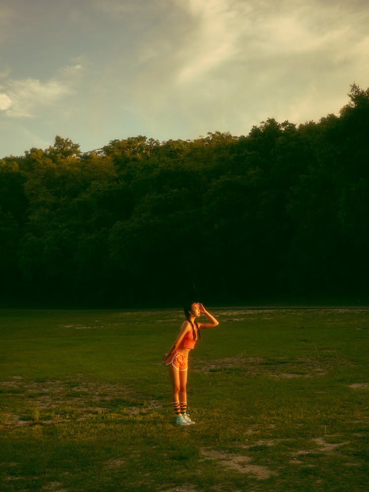 Girl Standing In Grassland And Looking Into Distance