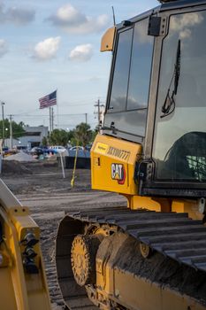 Close-up of an excavator at a construction site with an American flag in the background.
