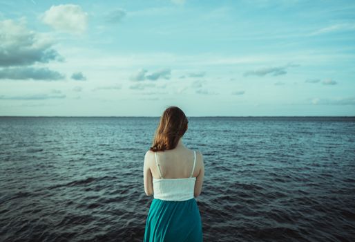 A peaceful moment, a woman looks out over the ocean, embracing nature's tranquility.