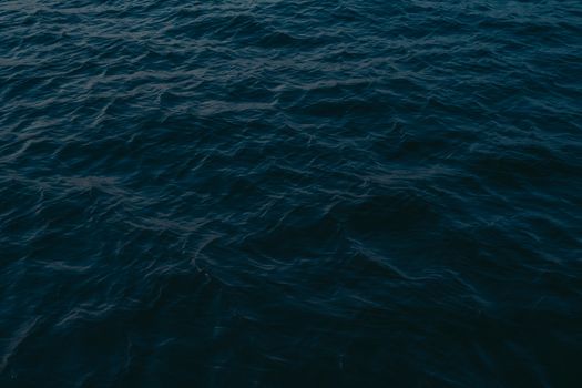 Explore the serene and dramatic ocean surface captured at twilight with rich textures and deep blue hues.