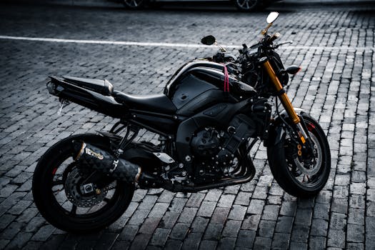 Close-up of a sleek black motorcycle parked on a cobblestone street, exuding modern elegance.