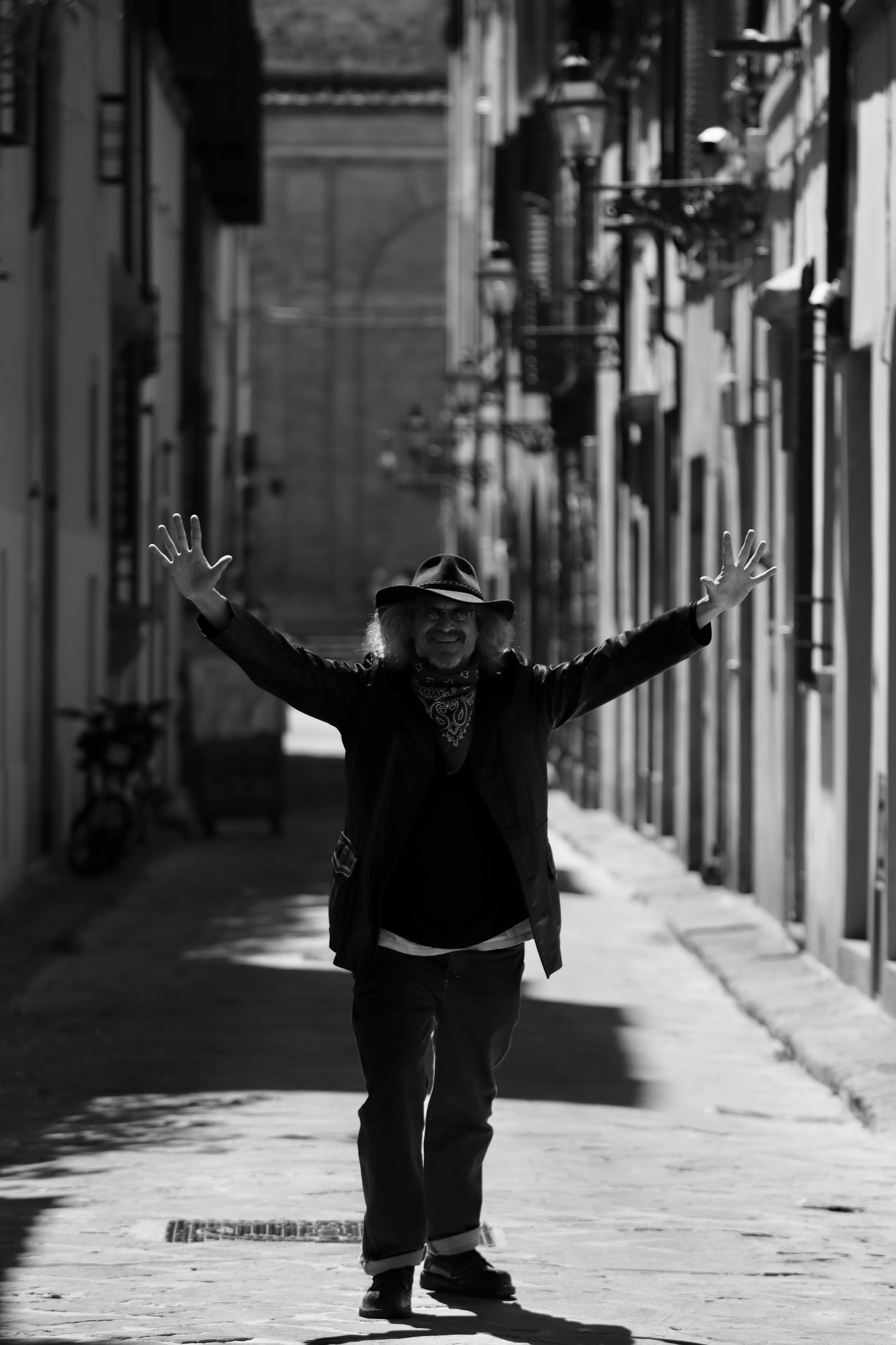 Black and white portrait of a man joyfully posing in a narrow street in Florence, Italy.