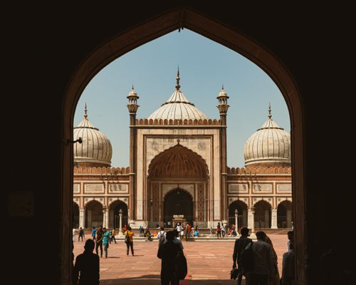 Free A captivating view through arches of the iconic Jama Masjid in New Delhi, bustling with visitors. Stock Photo