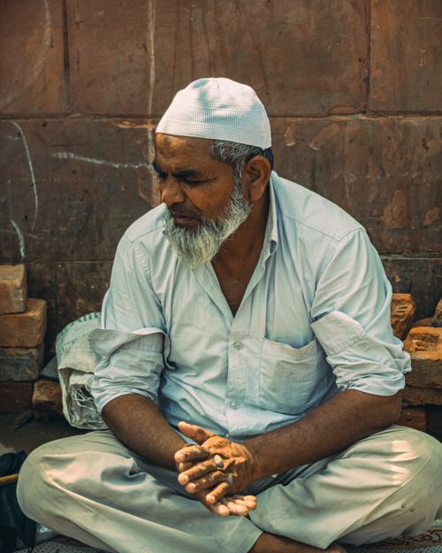 Free An elderly man wearing a prayer cap, sitting and praying on a street in Delhi, India. Stock Photo