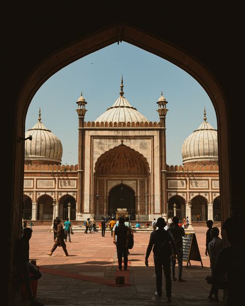 Free View of Jama Masjid, New Delhi with people walking through the archway on a sunny day. Stock Photo