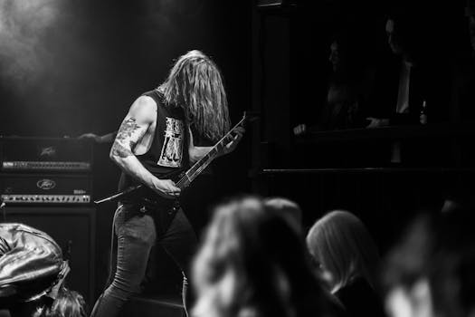 Energetic black and white photo of a guitarist rocking on stage during a live concert.