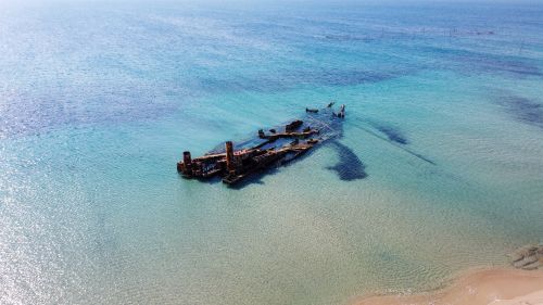 Free Drone view of a shipwreck in clear turquoise waters off Potamos Beach in Epanomi, Greece. Stock Photo