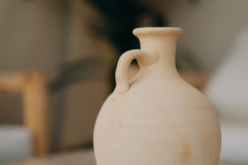 Petit vase déco en argile fait main posé sur une surface claire