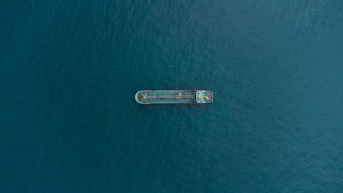 Free Aerial perspective of a cargo ship navigating through vast open waters, showcasing solitude and maritime commerce. Stock Photo