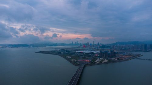 Free Aerial shot of a modern cityscape with waterfront view and cloudy sky at dusk. Stock Photo