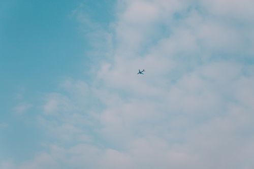Free An airplane flying high in a clear blue sky with scattered clouds. Perfect travel and aviation image. Stock Photo