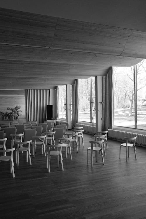 Free A Grayscale of Arranged Chairs in a Building Stock Photo