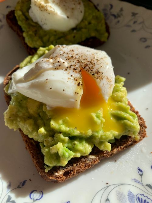 Free Savory avocado toast topped with a perfectly poached egg and seasoned with pepper. Stock Photo