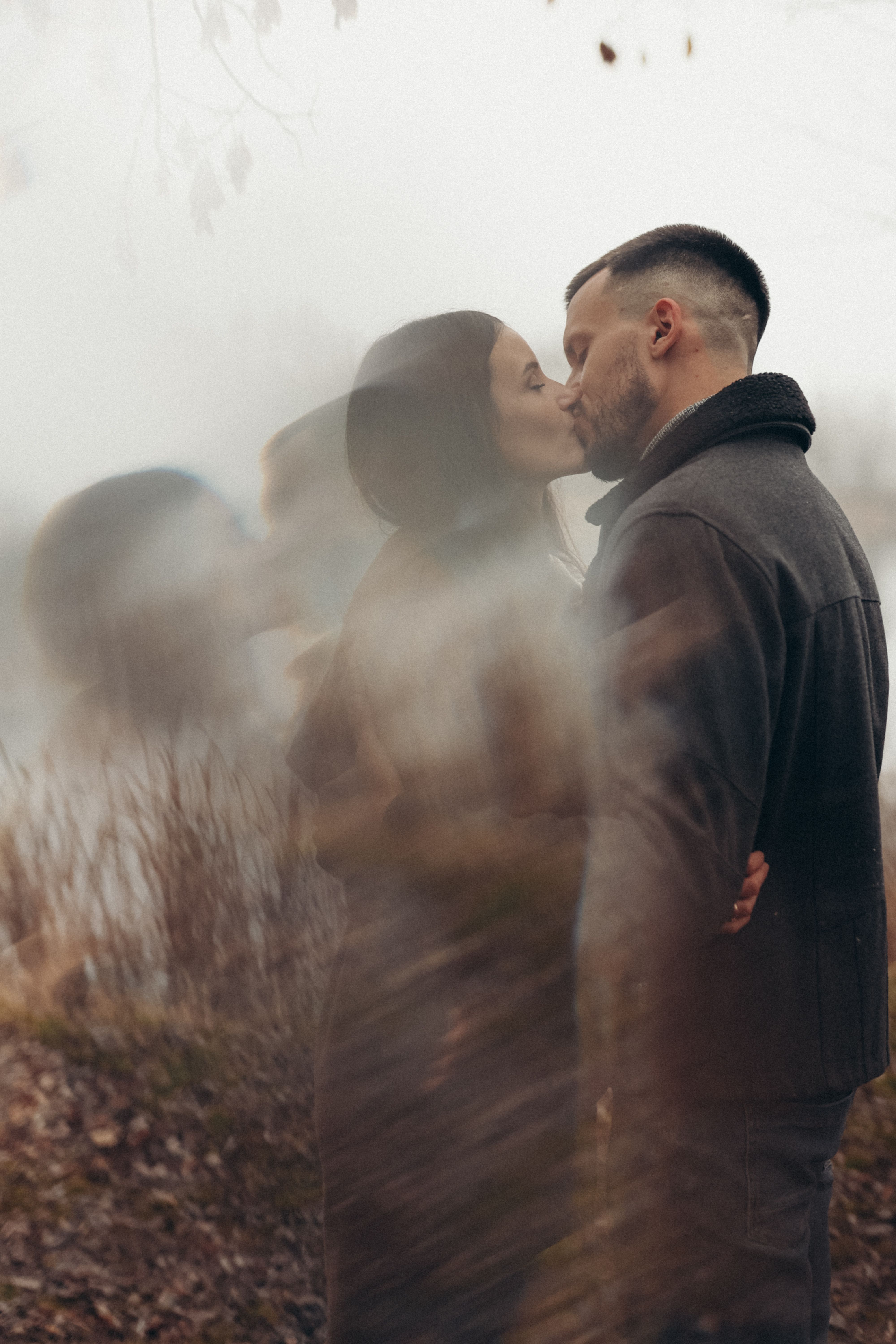 A couple embracing and kissing in an outdoor setting, creating a warm, romantic atmosphere.