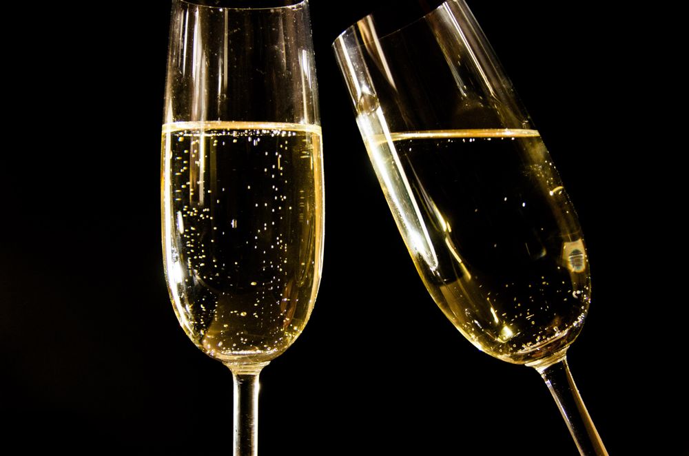 Calici di vino spumante dorato con bollicine su fondo nero