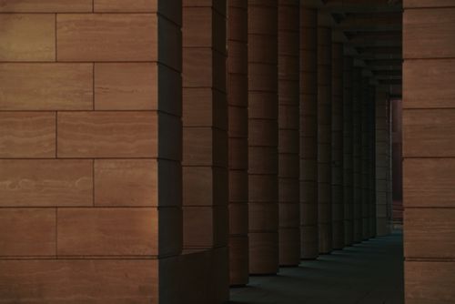 Free Symmetrical alignment of modern columns creating a moody architectural hallway ambiance at dusk. Stock Photo