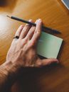 Person Holding Black Pen on Brown Wooden Table