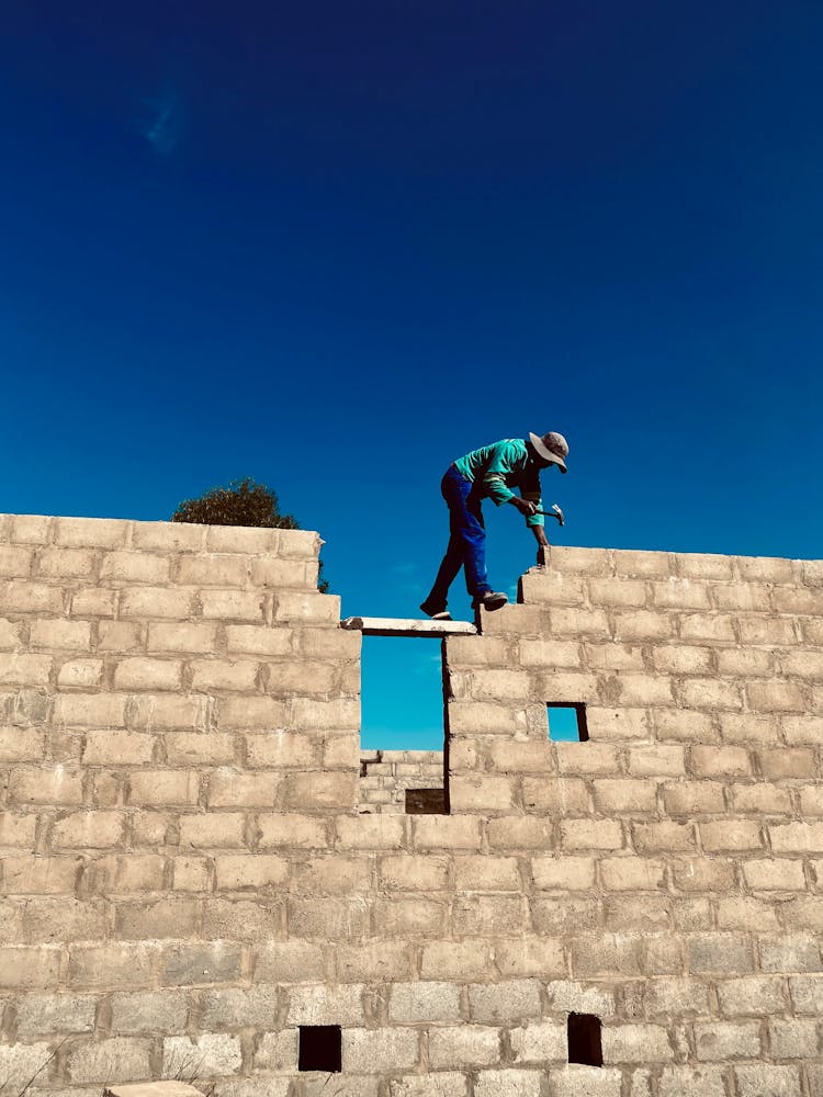 A Construction Worker Using A Hammer On Concrete Wall