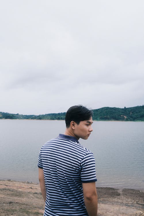 Free Man in Striped Polo Shirt Standing Near the Lake Stock Photo