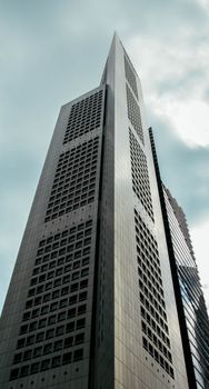 从低角度仰望，摩天大楼高耸于多云天空之下，展现了现代建筑的魅力