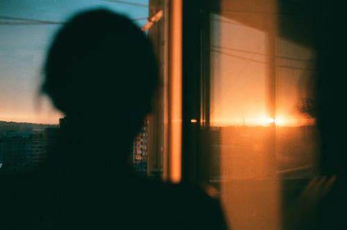 Free Silhouette of a person reflected on a window at sunset, creating a serene and reflective mood. Stock Photo